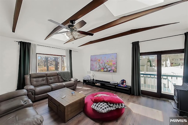 living room featuring vaulted ceiling with beams, a ceiling fan, and wood finished floors