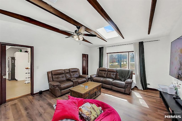 living area with vaulted ceiling with skylight, ceiling fan, baseboards, and wood finished floors