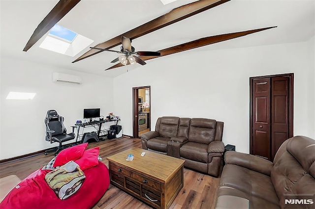 living area featuring ceiling fan, vaulted ceiling with skylight, wood finished floors, and a wall unit AC