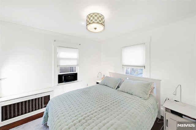 bedroom with crown molding, radiator, wood finished floors, and cooling unit