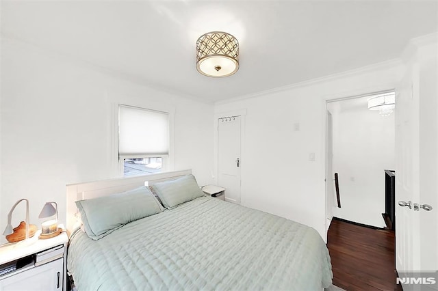 bedroom with crown molding and wood finished floors