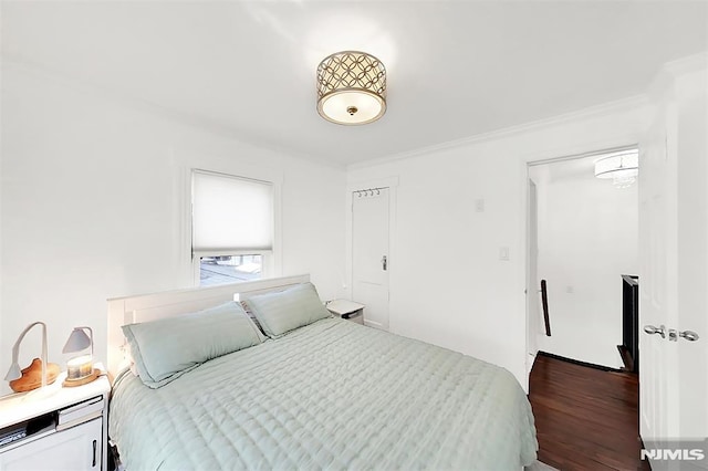 bedroom with dark wood-type flooring and crown molding