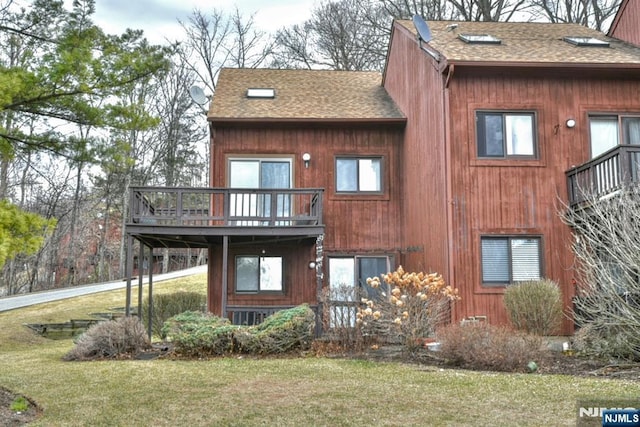 back of house with a yard and roof with shingles