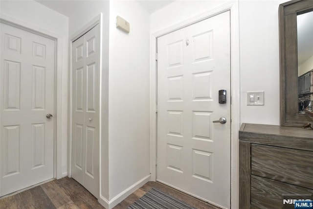 foyer featuring dark wood-type flooring and baseboards