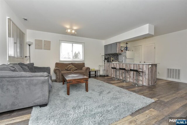 living room featuring dark wood finished floors, visible vents, and baseboards