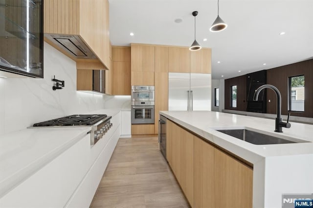 kitchen featuring hanging light fixtures, modern cabinets, stainless steel appliances, and a sink