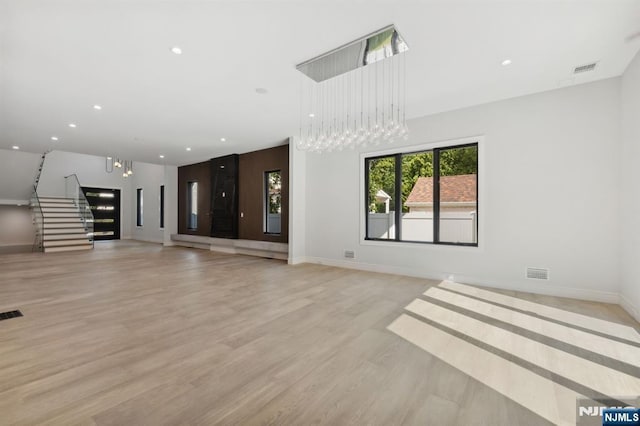 unfurnished living room with light wood-type flooring, visible vents, recessed lighting, baseboards, and stairs