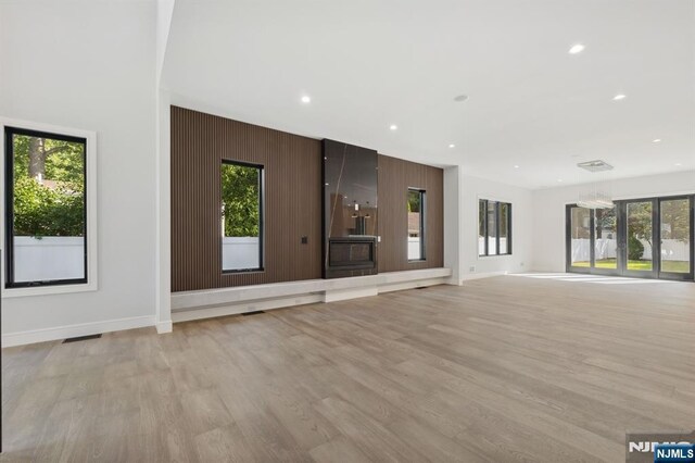 unfurnished living room with recessed lighting, baseboards, and light wood-style floors