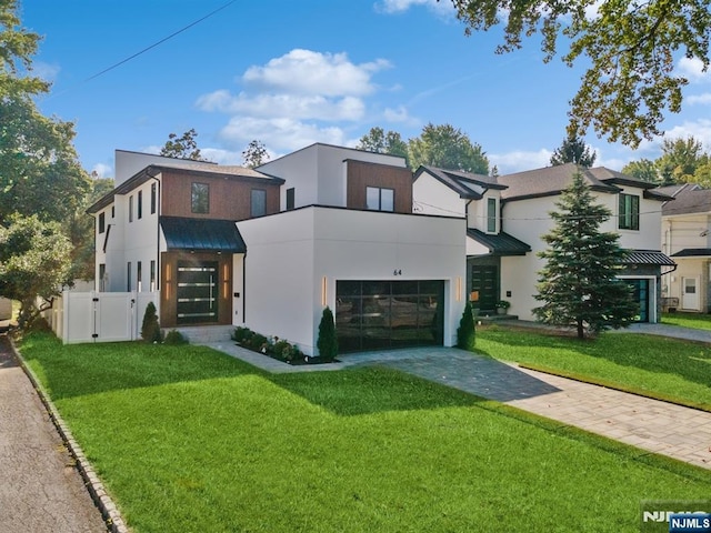 view of front of home featuring fence, driveway, stucco siding, a front lawn, and a garage