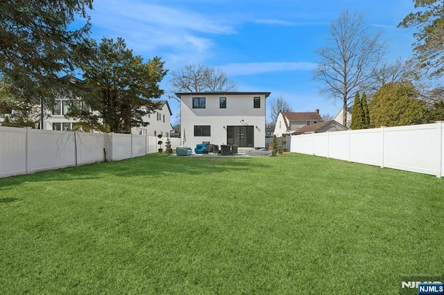 back of house with a patio area, a lawn, a fenced backyard, and stucco siding