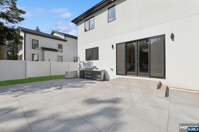 exterior space featuring french doors, an outdoor kitchen, and fence