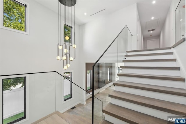 staircase featuring attic access, a high ceiling, recessed lighting, and wood finished floors