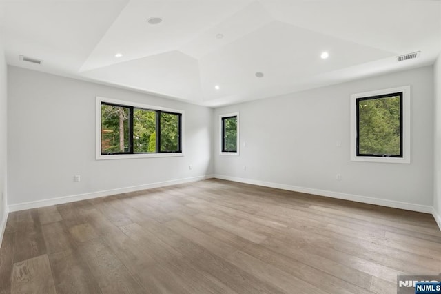 empty room with wood finished floors, visible vents, and baseboards