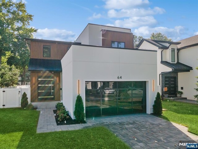 contemporary house with decorative driveway, stucco siding, and a gate