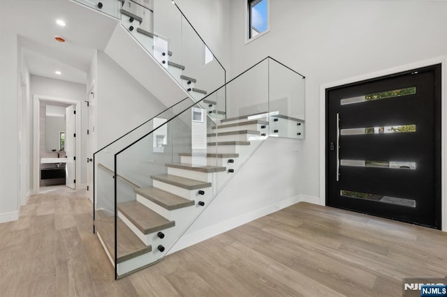 entrance foyer featuring a high ceiling, stairway, wood finished floors, and baseboards