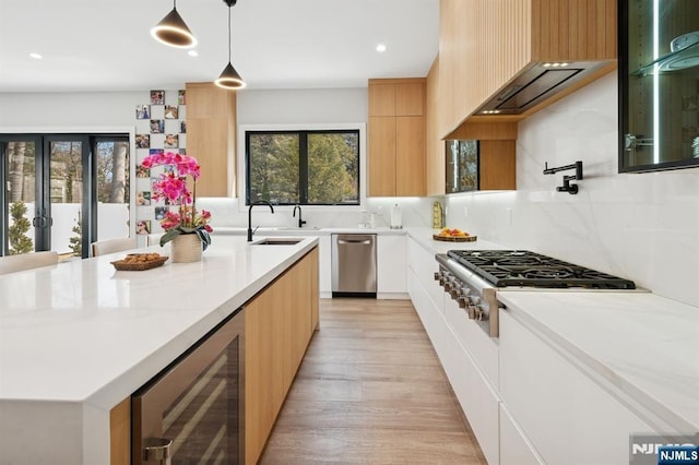 kitchen featuring modern cabinets, a sink, a center island, wine cooler, and appliances with stainless steel finishes