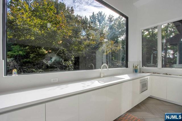 kitchen with white cabinets, modern cabinets, light countertops, and a sink