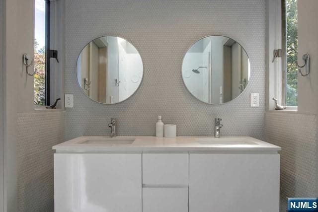 bathroom featuring double vanity, a wealth of natural light, and a sink