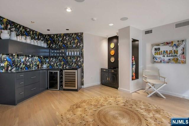 bar with visible vents, wine cooler, a bar, and wood finished floors