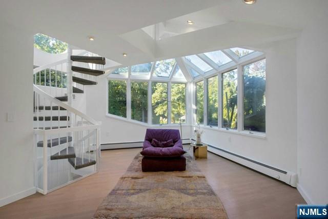 interior space featuring a baseboard heating unit, wood finished floors, and a sunroom