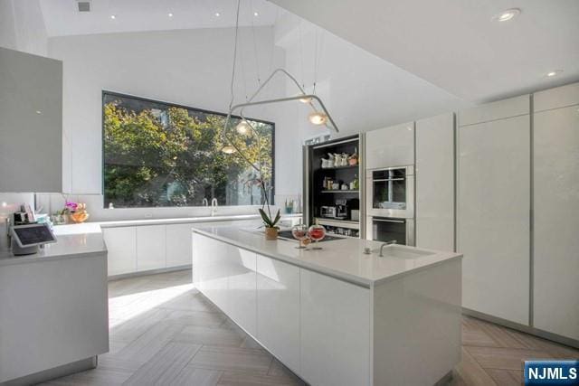 kitchen with a kitchen island, modern cabinets, white cabinets, and light countertops