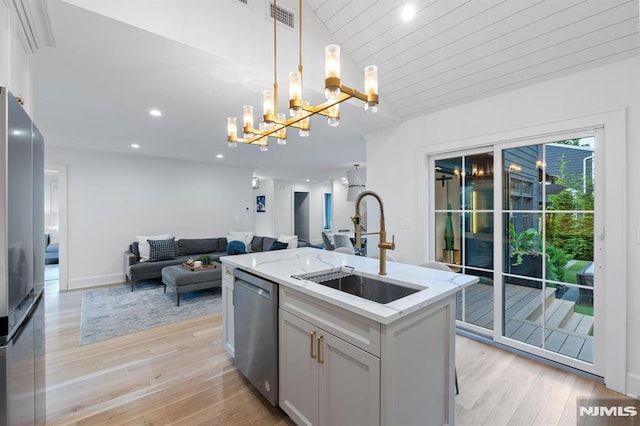 kitchen featuring visible vents, a sink, light stone counters, open floor plan, and stainless steel appliances