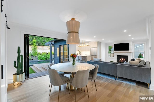 dining room featuring a barn door, light wood-style flooring, recessed lighting, and a fireplace