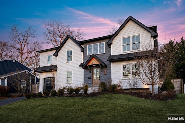 traditional-style house featuring a front lawn, driveway, and a shingled roof