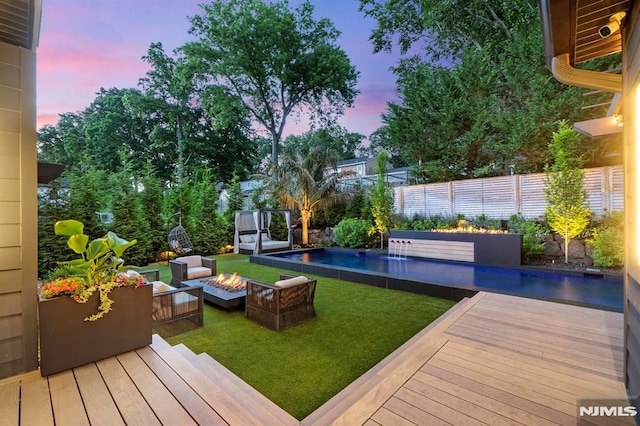 view of yard featuring a wooden deck, an outdoor pool, a fire pit, and a fenced backyard