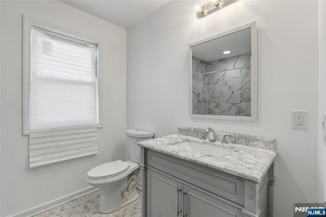 bathroom featuring vanity, toilet, a shower, and baseboards