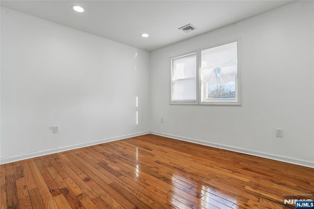 spare room featuring recessed lighting, visible vents, baseboards, and hardwood / wood-style floors