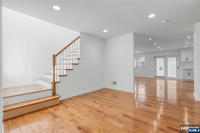 unfurnished living room with visible vents, light wood-style flooring, recessed lighting, stairway, and baseboards