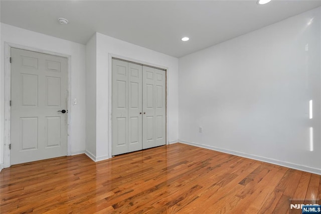 unfurnished bedroom with a closet, recessed lighting, baseboards, and light wood finished floors