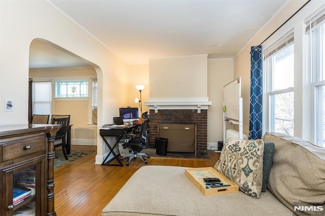 office featuring wood finished floors, arched walkways, a healthy amount of sunlight, and ornamental molding