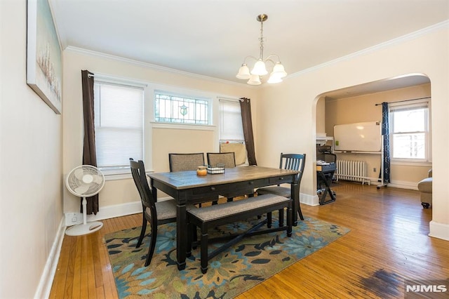 dining area with baseboards, radiator heating unit, arched walkways, hardwood / wood-style flooring, and crown molding