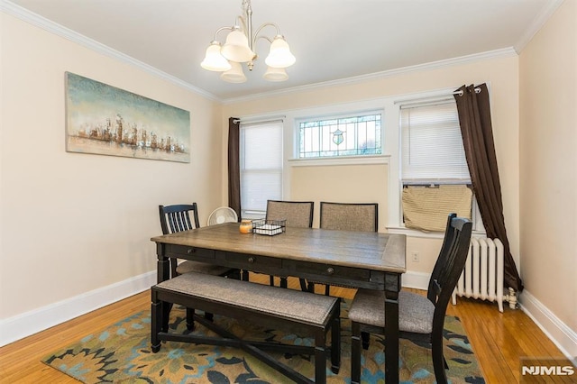 dining area with a notable chandelier, radiator heating unit, wood finished floors, and baseboards