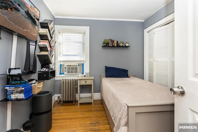 bedroom with crown molding, baseboards, radiator heating unit, cooling unit, and wood finished floors