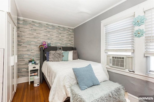 bedroom featuring crown molding, baseboards, dark wood-type flooring, an accent wall, and cooling unit