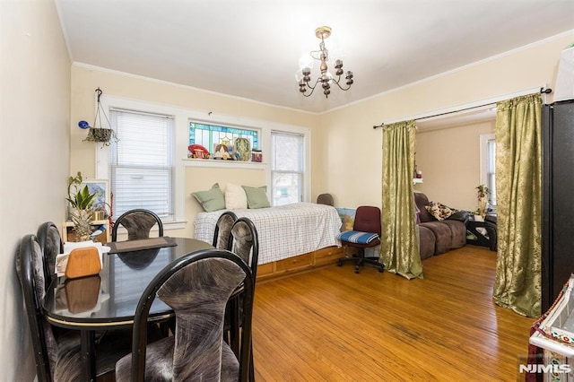 bedroom with crown molding, a notable chandelier, and wood finished floors