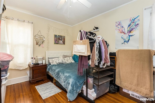 bedroom with a ceiling fan, crown molding, baseboards, and wood finished floors