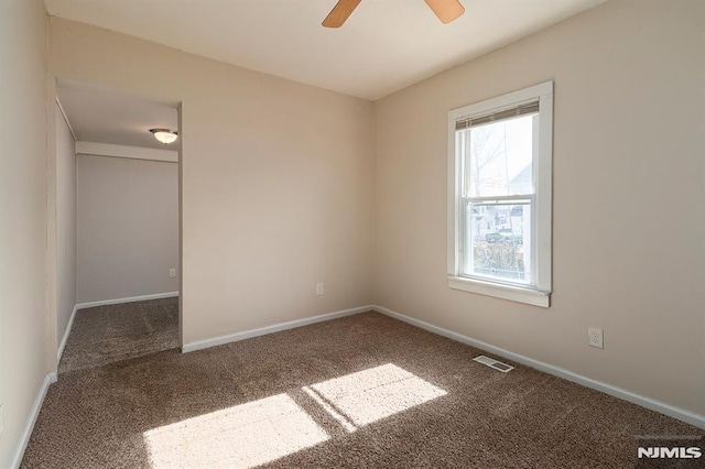 carpeted spare room featuring a ceiling fan, baseboards, and visible vents