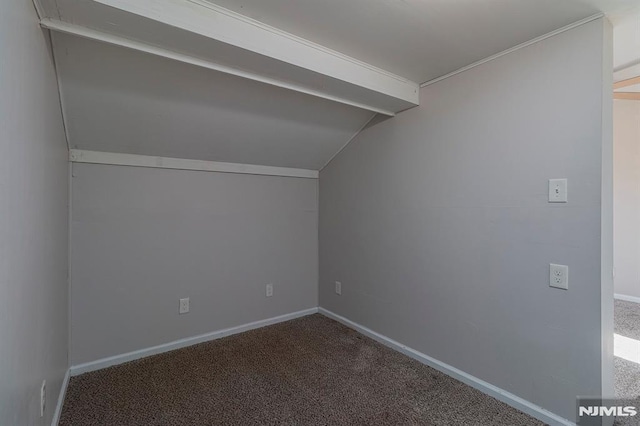 additional living space featuring baseboards, vaulted ceiling with beams, and carpet