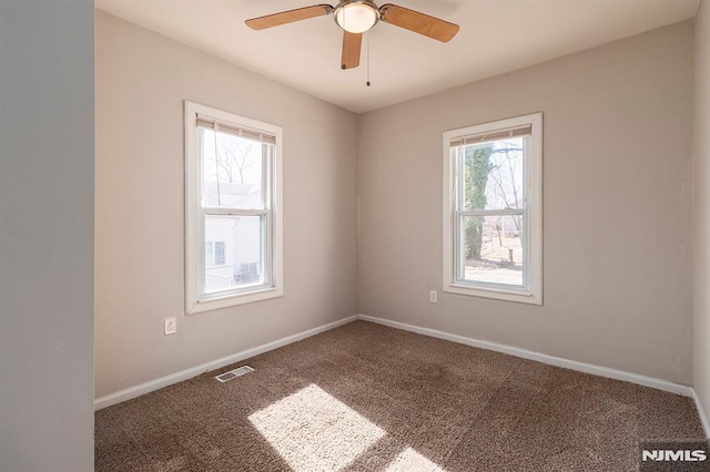 spare room with a ceiling fan, carpet flooring, visible vents, and baseboards