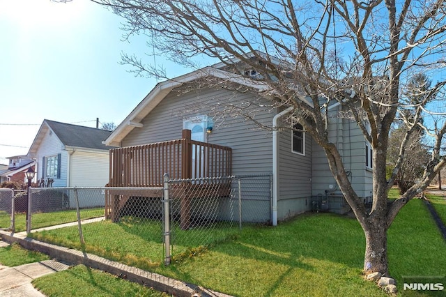 view of side of home featuring a lawn and fence