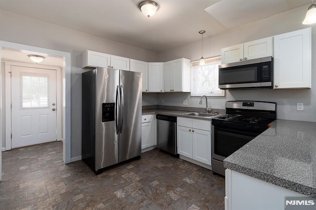 kitchen with a sink, stone finish flooring, white cabinetry, and stainless steel appliances