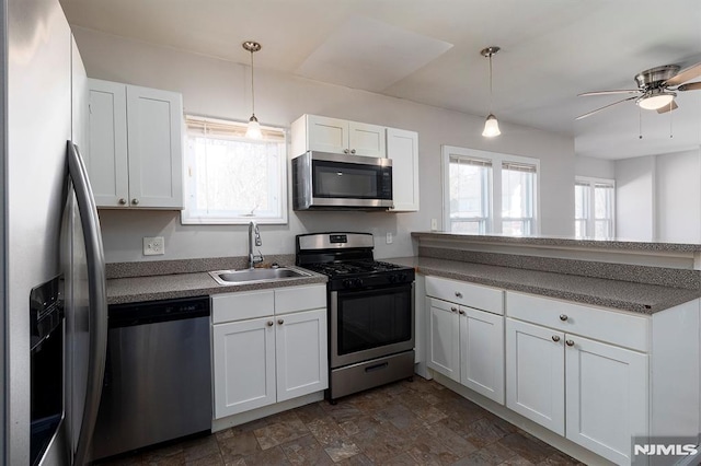 kitchen featuring a peninsula, hanging light fixtures, white cabinets, stainless steel appliances, and a sink