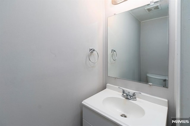 bathroom featuring visible vents, toilet, and vanity