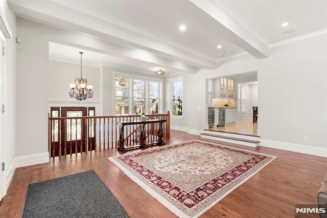 entryway with crown molding, baseboards, beam ceiling, wood finished floors, and a notable chandelier