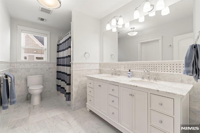 full bath with a sink, visible vents, toilet, and double vanity