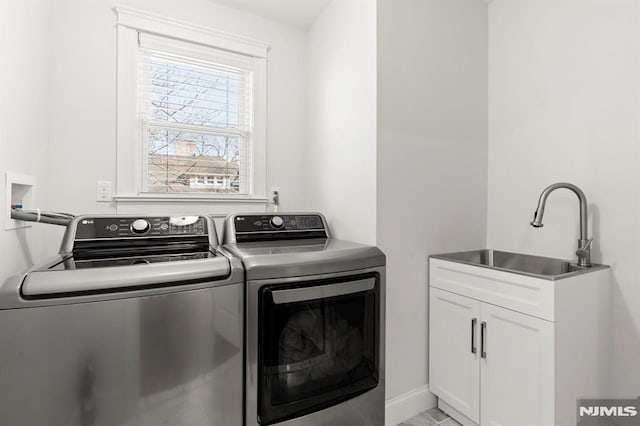 laundry area featuring a sink, baseboards, cabinet space, and washing machine and dryer